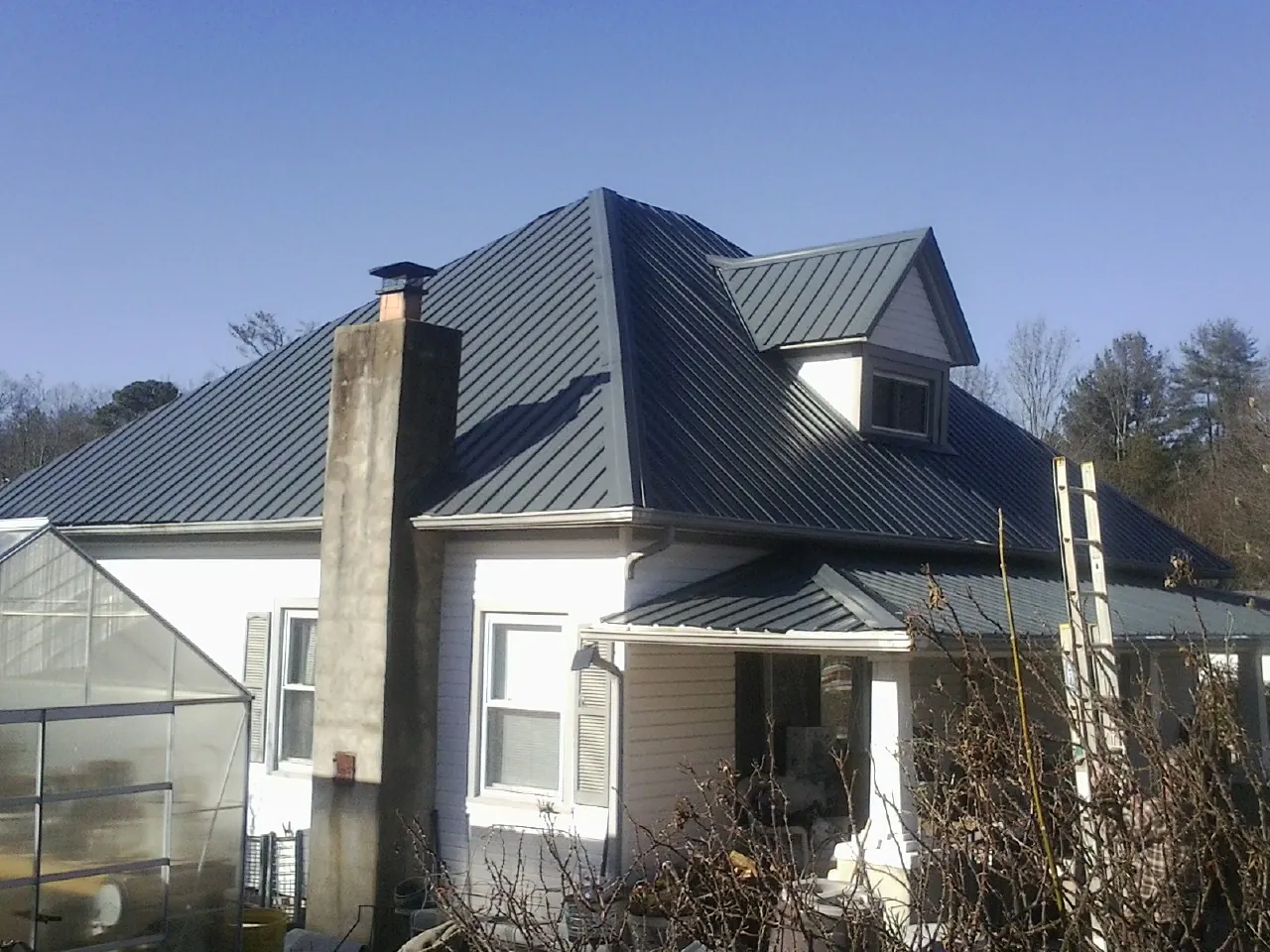 Dark blue standing seam metal roof on a white farmhouse with dormer — Slate & Tile Roof Repair by Roofing Brothers in Shawano