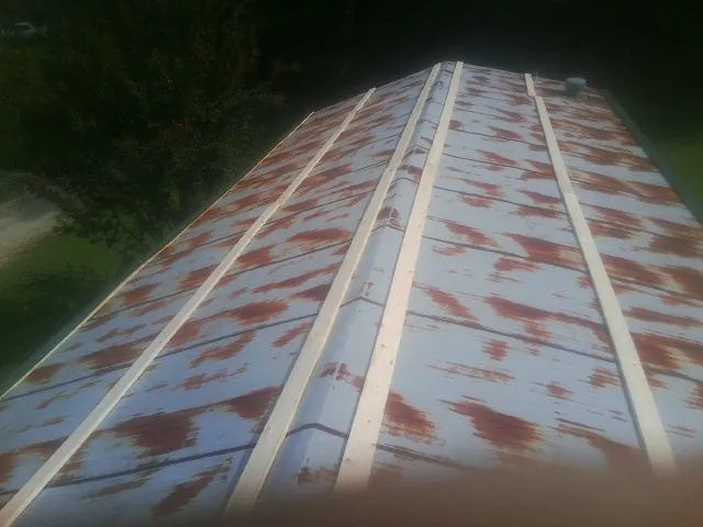 Rusted metal roof panels with new wood purlins before replacement — Storm Damage Roof Repair in Shawano by Roofing Brothers