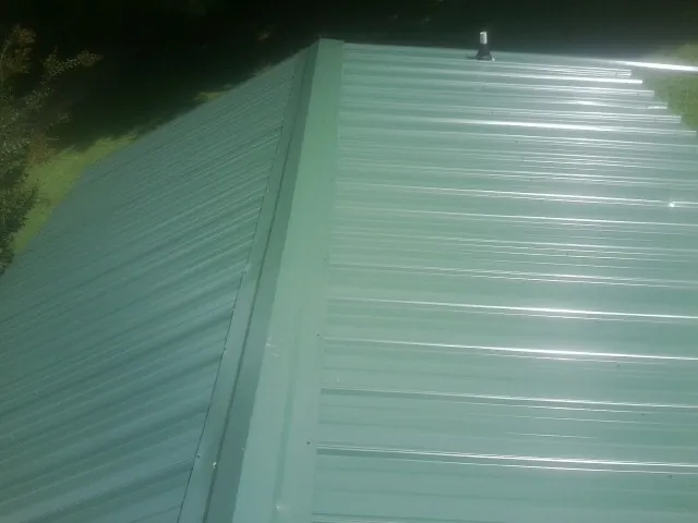 New green metal panels meeting at the ridge of a roof — Flat Roof Repair work by our crew in Shawano