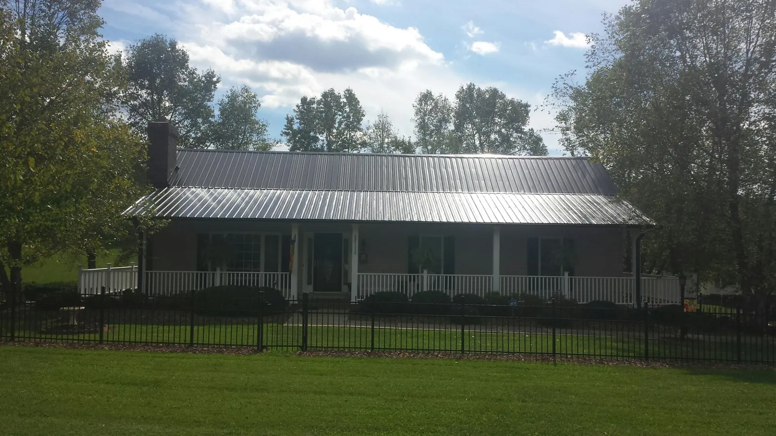 Gray metal roof on a brick ranch with a full width front porch — Gutter Guard Installation work by our crew in Shawano